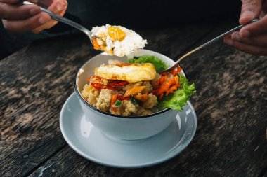 Pirinç, sebze ve sahanda yumurta ile dolu canlı bir kase, kırsal ahşap bir masaya kurulmuş besleyici ve lezzetli bir yemek yaratıyor.