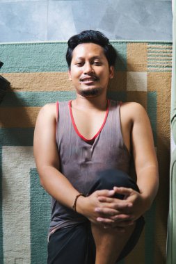 Spor yapmak için içeride bacak esnetme egzersizi yapan bir adam. Evde sağlık, fiziksel sağlık ve refahı teşvik eder.