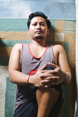 Spor yapmak için içeride bacak esnetme egzersizi yapan bir adam. Evde sağlık, fiziksel sağlık ve refahı teşvik eder.