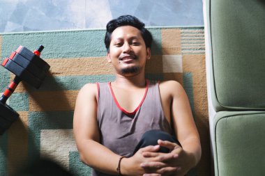 Spor yapmak için içeride bacak esnetme egzersizi yapan bir adam. Evde sağlık, fiziksel sağlık ve refahı teşvik eder.