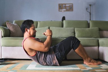 Konforlu bir oturma odasında karın egzersizi yapan aktif bir birey, ev ortamında ilham kaynağı sergiliyor.