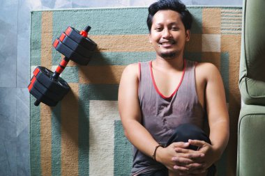 Spor yapmak için içeride bacak esnetme egzersizi yapan bir adam. Evde sağlık, fiziksel sağlık ve refahı teşvik eder.