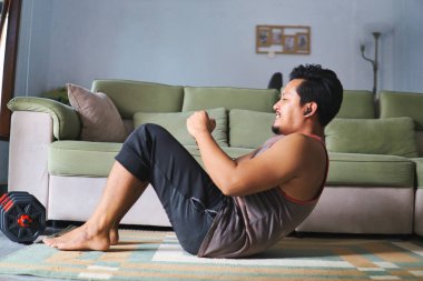 Konforlu bir oturma odasında karın egzersizi yapan aktif bir birey, ev ortamında ilham kaynağı sergiliyor.