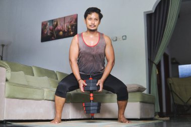 Spor salonundaki dambılları kullanarak ağırlık çalışması yapan kişi spor ve dayanıklılığı arttırır.