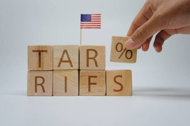 Tahta bloklar 'gümrük vergileri' ni küçük bir Amerikan bayrağı eşliğinde bir yüzdelik blok ekleyerek hecelemek için düzenlendi. ABD ticaret politikası, ithalat vergileri, ihracat vergileri ve uluslararası iş yönetmelikleri kavramı.