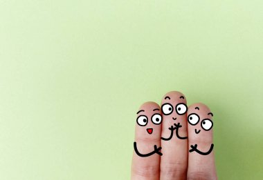 Three fingers are decorated as three person. They are happy.