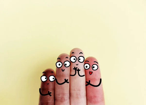 Four fingers are decorated as four person. They are from different places with different skin color and they are happy to be together.