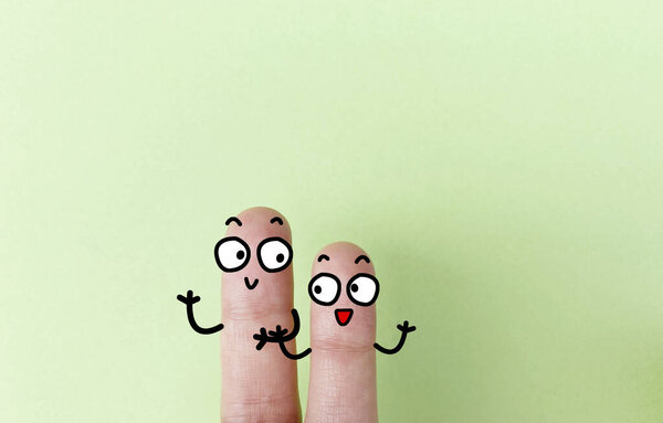 Two fingers are decorated as two person. They are happy.