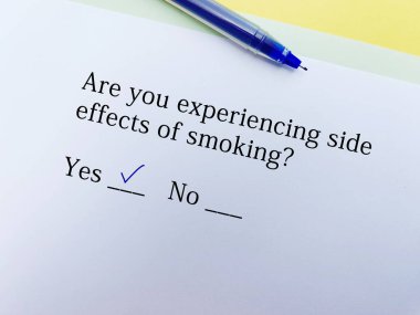 Bir kişi yan etkiler hakkındaki soruyu cevaplıyor. Sigara içmenin yan etkilerini yaşıyor..