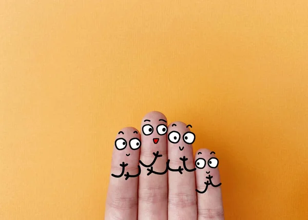 Four fingers are decorated as four person. They are happy.