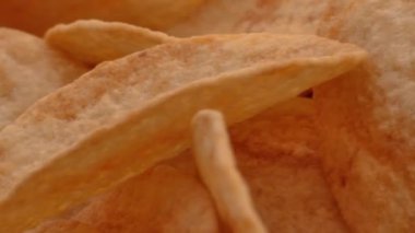Peynir aromalı patates cipsi yığını, beyaz arka planda, yüzeyde dönerken büyük detaylarla izleniyor..
