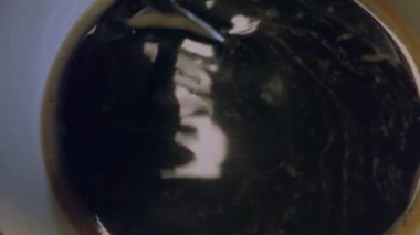 Kahveyi bir fincanda karıştırırken yakından görülüyor.