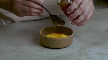 Karışıma bal ekleyen şekerlemeci, daha sonra küçük bir kapta kaşıkla sulandırmak için.