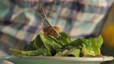 Çatalla salata yiyen kişi, tabağa ve salataya yakından bakın..