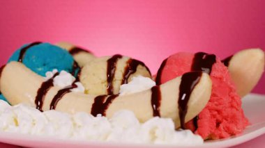 Onlar çikolata şurubu ve küçük tatlılar servis ederken, muz pembe bir arka planda bölünmüş