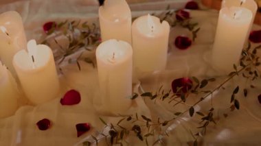 Mum ve gül yapraklarıyla süslenmiş romantik bir yemek masası.