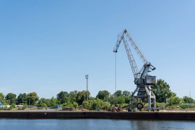 Usti Nad Labem, Çek Cumhuriyeti - 22 Haziran 2025: Endüstriyel vinç Usti Nad Labem 'de açık mavi gökyüzü ve yeşillikle Elbe Nehri' nin yanında duruyor