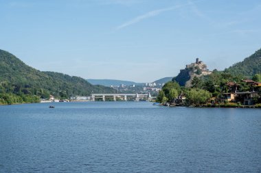 Yeşil tepeler ve büyüleyici binalarla çevrili sakin bir nehrin manzarası doğal güzellikleri ve tarihsel unsurları gözler önüne seriyor.