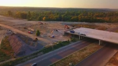 Şehrin dışında köprüsü olan bir yol kavşağı inşaatı. Akşam vakti güzel bir günbatımı. Yüksek kaliteli FullHD görüntüler
