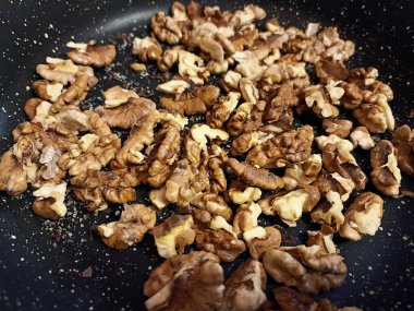 Ceviz çekirdekleri tavada kızarır. Yemek pişirme süreci.