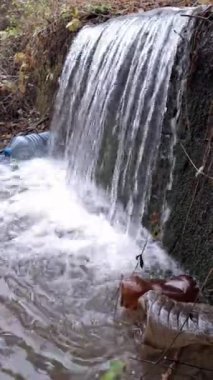 Plastik şişelerle kirletilmiş, atıkların çevresel etkisini vurgulayan ve kirliliğin ekosistemler üzerindeki etkisi hakkında farkındalığı artıran doğal bir ortamda bir şelale.