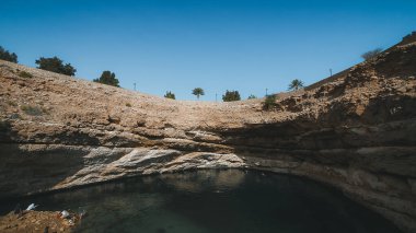 Bimmah, Oman,  Bimmah Sinkhole in Oman, where fresh and salt water combine. Beautiful turquoise blue splendour. 600 meters separate the northeast coast of Oman. People spimming and relaxing. clipart