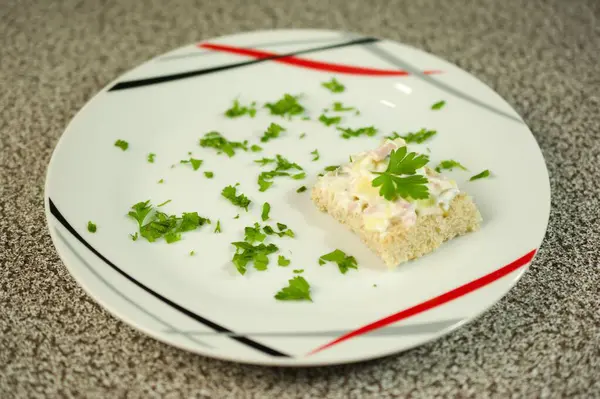 Kremalı salata ve maydanozla kaplı lezzetli bir kare ekmek dilimi modern tabak tasarımında dağınık yeşilliklerle güzelce sunuluyor. Her durum için mükemmel.!