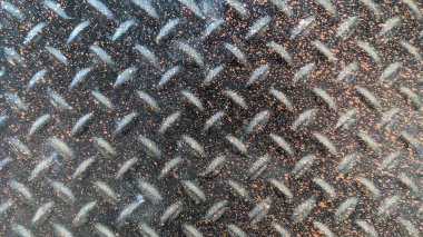 A textured metal surface with a diamond plate pattern. This pattern consists of raised, diamond-shaped ridges, providing a non-slip texture. The surface appears metallic and slightly worn, often used for industrial flooring or stairs. clipart