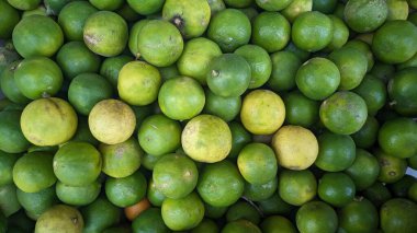 Koyu yeşilden koyu yeşile gölgeli yeşil limon yığını ve sarımsı renkler. Yakın bir şekilde paketlenmişler, dokulu ve canlı bir görünüm yaratıyorlar..