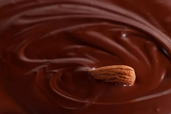 Bademler erimiş çikolatada boğuluyor. Çikolata arkaplanı. Seçici odak