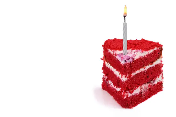 Bir dilim kırmızı kadife pasta ve doğum günü kutlamasının sembolü olarak yanan bir mum. Boşluğu kopyala.
