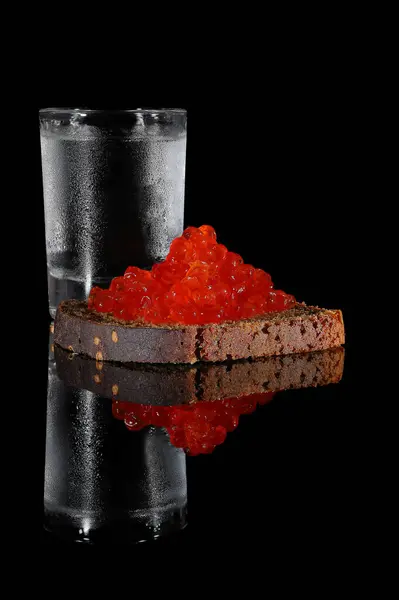 Bir dilim çavdar ekmeğiyle kırmızı havyar şeklinde votka ve aperatif. Bir tek soğuk votka yoğuşmuş..