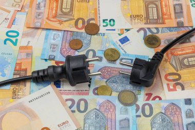 Avrupa banknotları, madeni paralar ve ev elektrik tüketicilerinin elektrik kabloları. Tasarruf ve makul elektrik tüketimi kavramı.