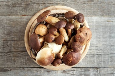 Taze yaban domuzu ve çam mantarı bir sepetin içinde, masanın üstünde.