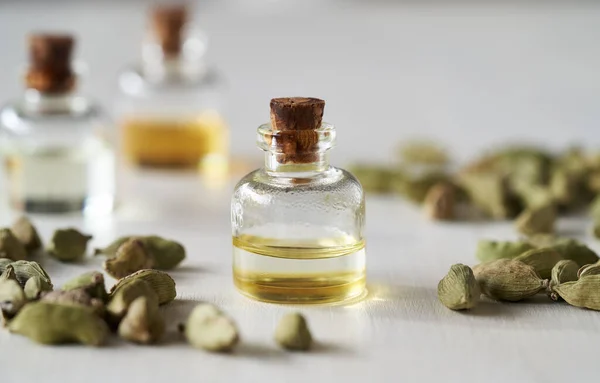 stock image A bottle of aromatherapy essential oil with cardamom seeds on a white background