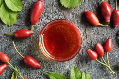 Kırmızı gül tohumu yağı ve koyu arka planda taze gül kalçası.