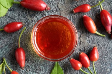 Red rose hip seed oil in a bowl with fresh berries, top view