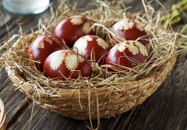 Easter eggs colored with onion peels in a wicker basket on a wooden table