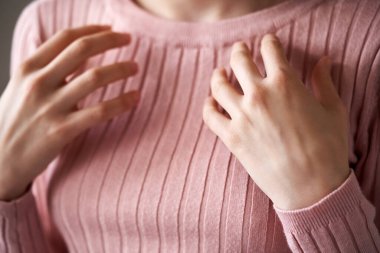 Hands of a young woman practicing EFT or emotional freedom technique - tapping on the collarbone point
