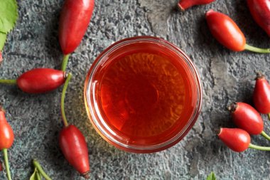 Red rose hip seed oil with fresh berries, top view