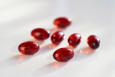 Red krill oil pills or globules on a white background