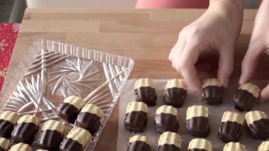 Hands arranging homemade Christmas cookies on a plate