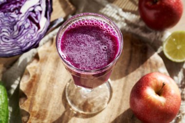 A glass of fresh homemade purple cabbage juice on a wooden table