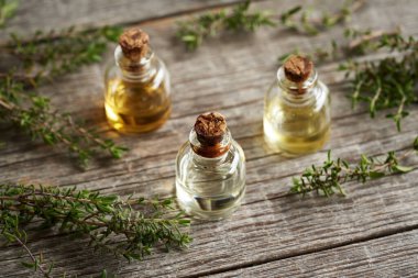 Bottles of aromatherapy essential oil with fresh thyme 