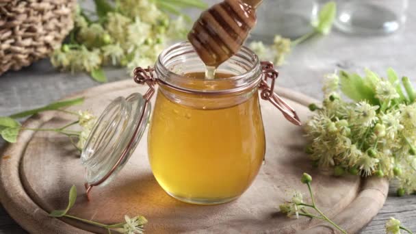Honey Flowing Dipper Glass Jar Fresh Linden Flowers Background — Wideo stockowe