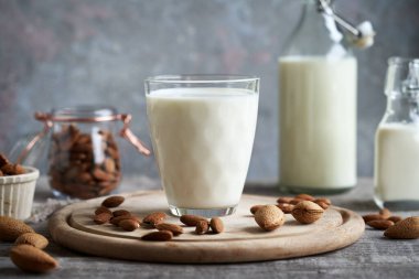 Bardakta vejetaryen badem sütü ve masada şişe.