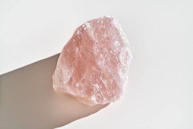 Rose quartz stone with a shadow on white background