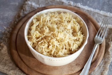 Fermented cabbage or sauerkraut in a white bowl with a fork