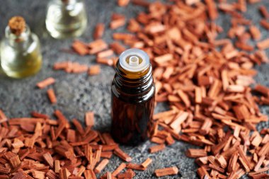 A dropper bottle of essential oil with red sandalwood chips on a table
