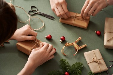 Childrens' hands wrapping Christmas present in ecological recycled paper